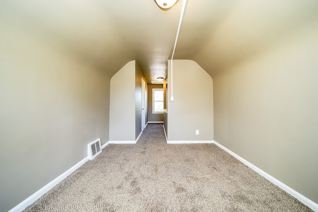 additional living space featuring visible vents, baseboards, carpet floors, and vaulted ceiling