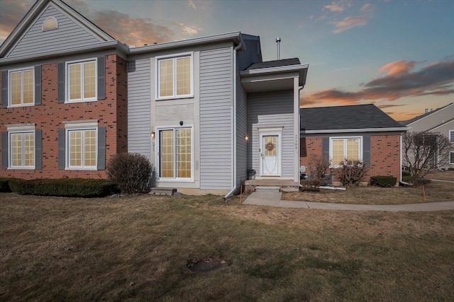 view of front of property featuring a lawn and brick siding