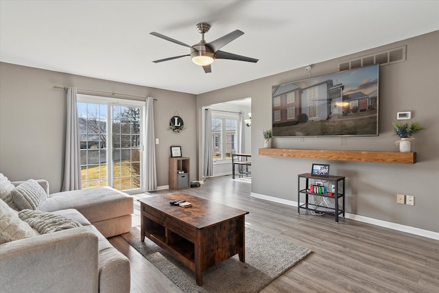 living room featuring visible vents, plenty of natural light, baseboards, and wood finished floors