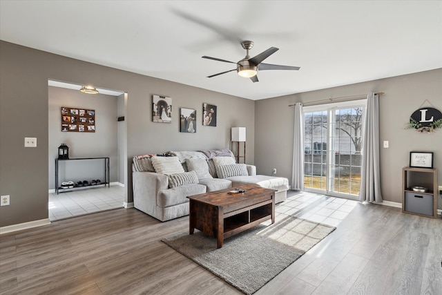 living room featuring wood finished floors, baseboards, and ceiling fan