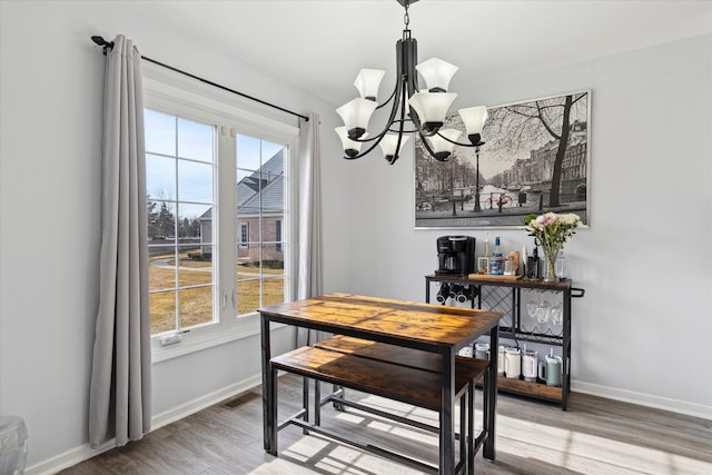 dining room with visible vents, wood finished floors, baseboards, and a chandelier