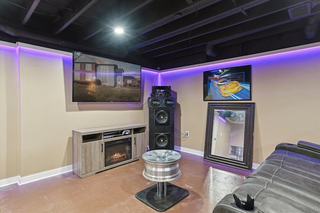 interior space with a glass covered fireplace, visible vents, concrete floors, and baseboards