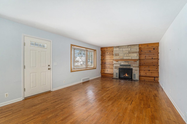 unfurnished living room featuring a fireplace, wood finished floors, visible vents, and baseboards