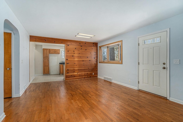 foyer entrance featuring arched walkways, visible vents, light wood-type flooring, and baseboards