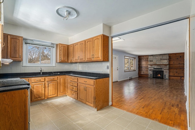 kitchen with brown cabinets, open floor plan, backsplash, and stainless steel range with electric cooktop