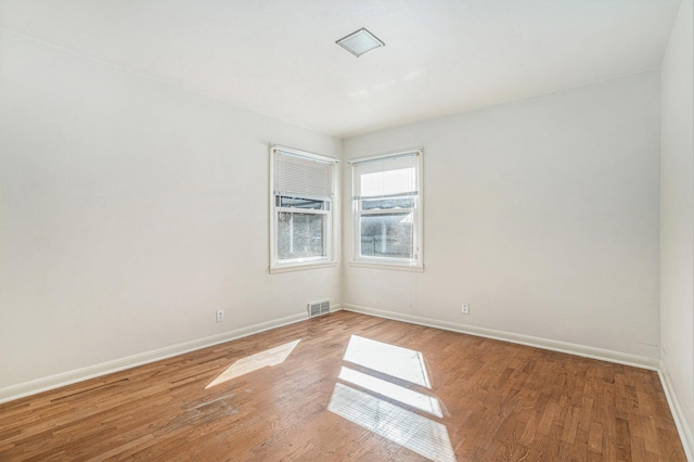 spare room featuring baseboards, visible vents, and light wood-type flooring