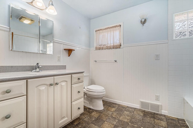 full bath featuring visible vents, toilet, wainscoting, a shower, and vanity