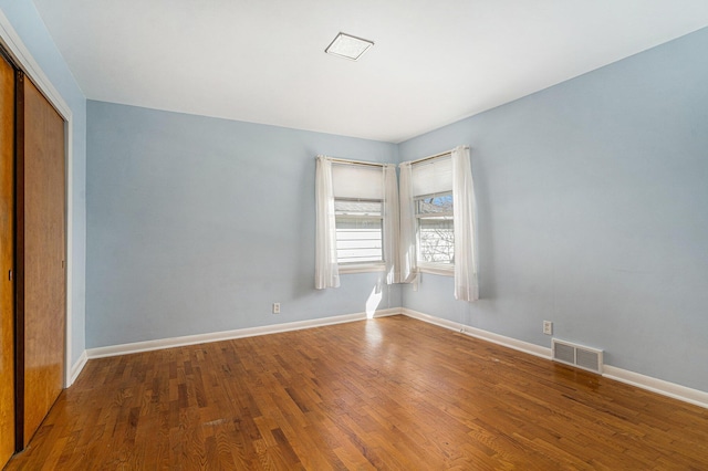 empty room featuring visible vents, baseboards, and wood finished floors