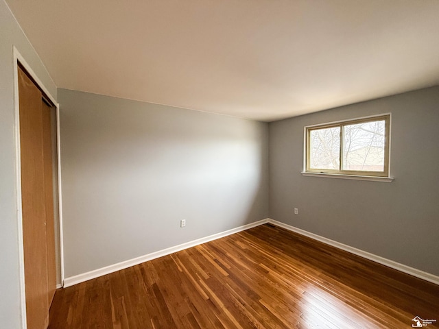 empty room featuring dark wood finished floors and baseboards