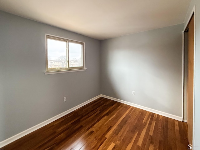 unfurnished room with dark wood finished floors and baseboards