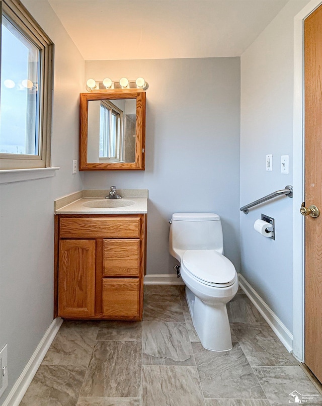 half bath featuring toilet, vanity, and baseboards