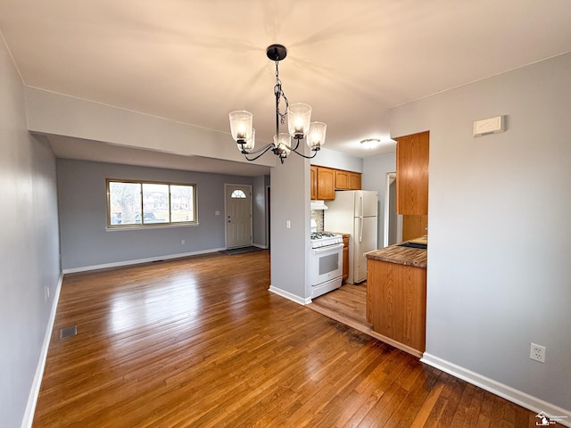 kitchen featuring visible vents, open floor plan, white appliances, wood-type flooring, and brown cabinetry