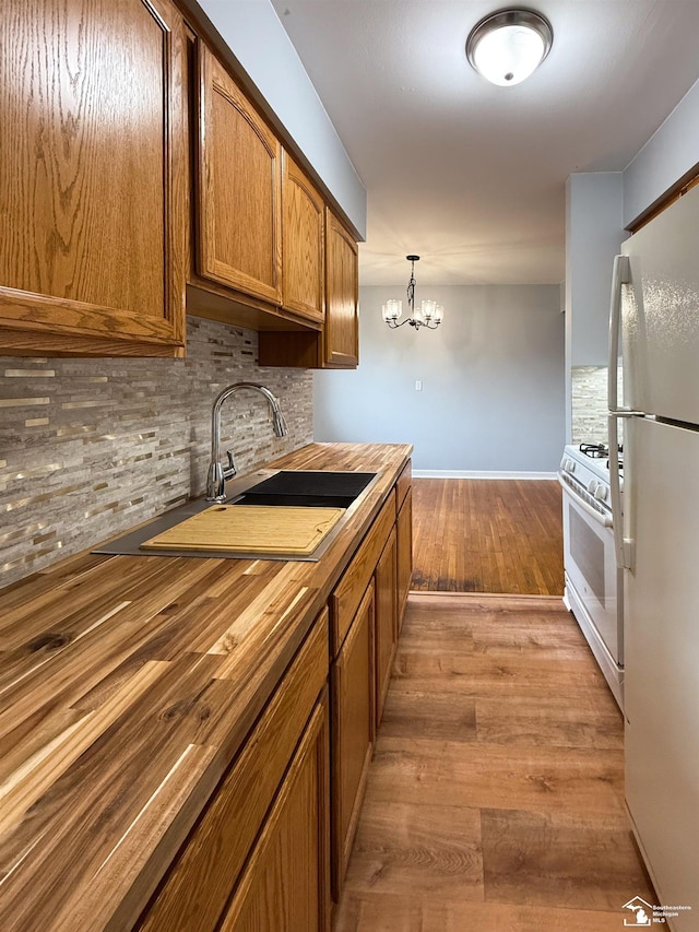 kitchen featuring backsplash, wood finished floors, white appliances, wood counters, and a sink