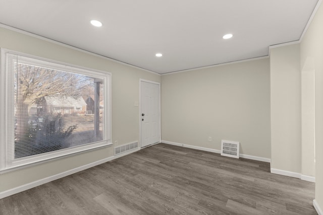 spare room featuring visible vents, crown molding, and wood finished floors