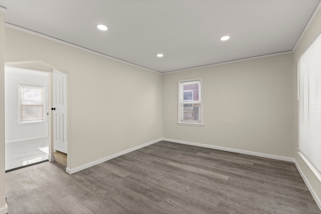 spare room featuring recessed lighting, crown molding, baseboards, and dark wood-style flooring