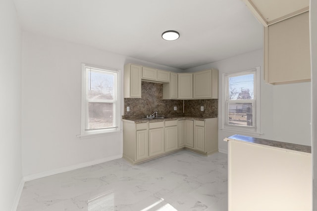 kitchen with cream cabinets, baseboards, marble finish floor, and a sink