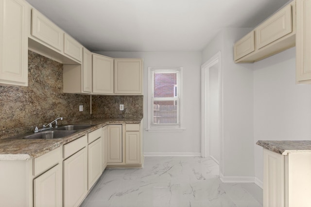 kitchen featuring tasteful backsplash, baseboards, cream cabinetry, marble finish floor, and a sink