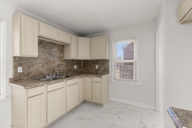 kitchen featuring backsplash, marble finish floor, cream cabinets, and a sink