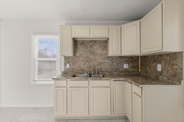 kitchen with a sink, baseboards, backsplash, and marble finish floor