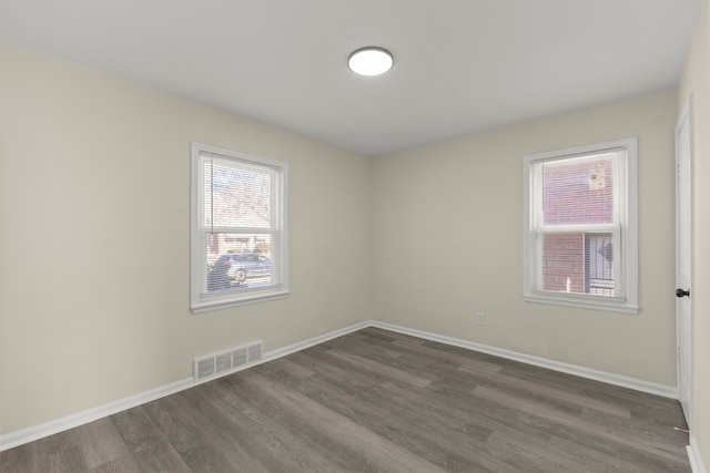 empty room with visible vents, baseboards, and dark wood-style flooring