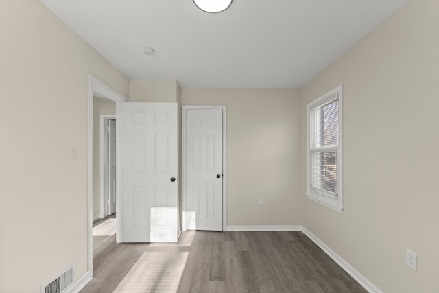 unfurnished bedroom with visible vents, baseboards, and dark wood-type flooring