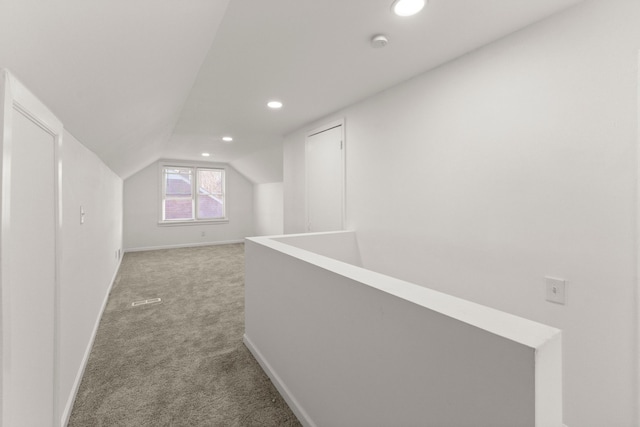 hallway featuring baseboards, lofted ceiling, recessed lighting, light carpet, and an upstairs landing