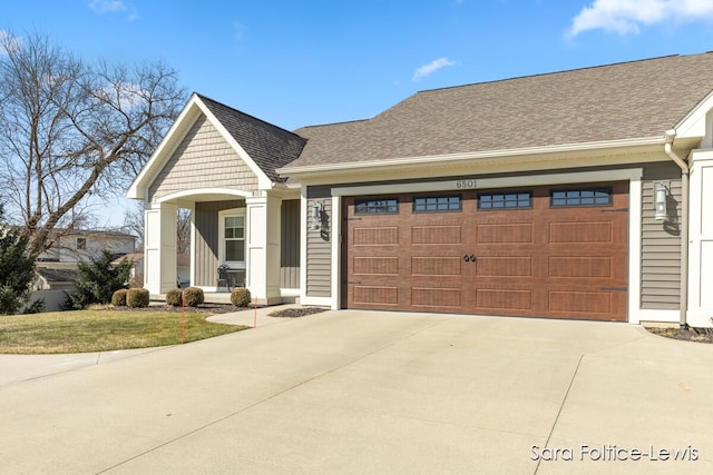 view of front of property featuring a front yard, a garage, driveway, and roof with shingles