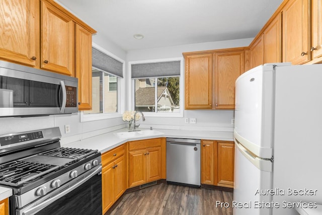 kitchen featuring a sink, light countertops, brown cabinetry, stainless steel appliances, and dark wood-style flooring