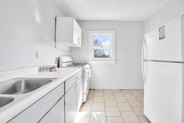 kitchen with light countertops, light tile patterned flooring, white cabinets, white appliances, and a sink