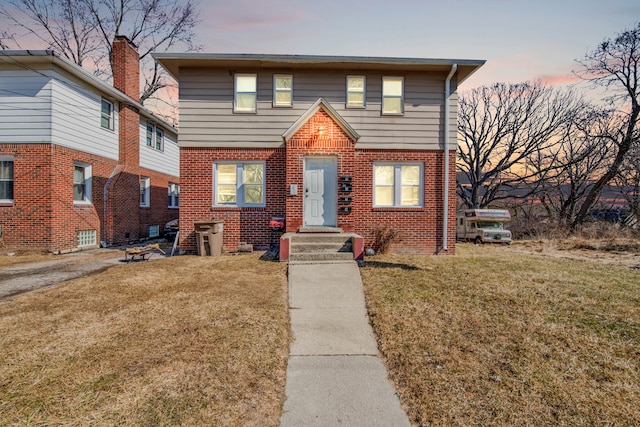 view of front of house with brick siding and a lawn