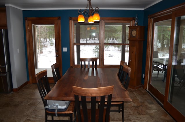 dining space featuring baseboards, a notable chandelier, ornamental molding, and stone finish floor