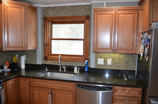 kitchen featuring tasteful backsplash, appliances with stainless steel finishes, dark stone counters, and a sink