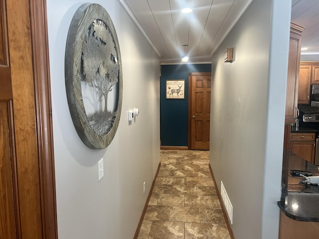 hall featuring visible vents, baseboards, ornamental molding, and stone finish floor