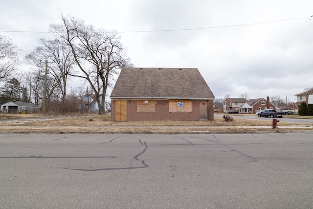 view of side of home with brick siding, a residential view, and roof with shingles