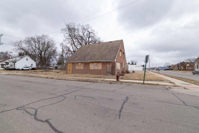 view of front of home featuring a residential view, brick siding, and a shingled roof