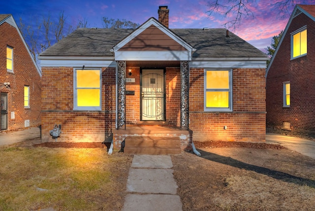 bungalow-style house featuring brick siding and a chimney