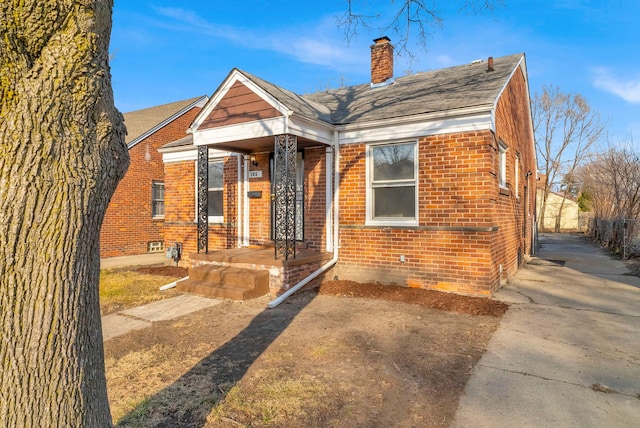 bungalow-style home featuring brick siding and a chimney