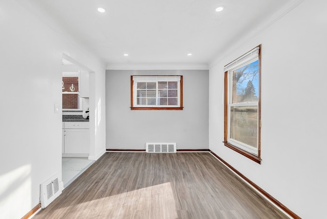 empty room featuring wood finished floors, visible vents, and baseboards