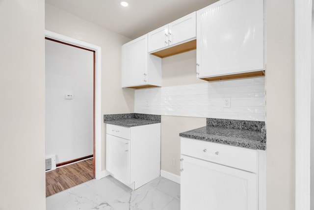 kitchen with visible vents, marble finish floor, backsplash, white cabinetry, and baseboards