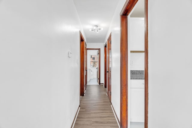 corridor featuring light wood-type flooring and baseboards