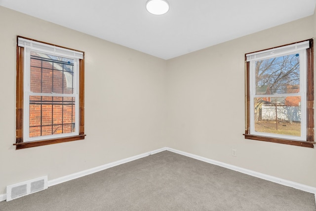 spare room with carpet flooring, baseboards, and visible vents