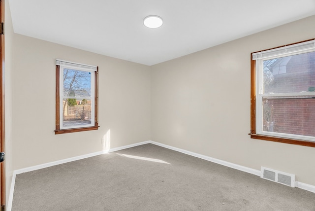 spare room with carpet flooring, baseboards, and visible vents