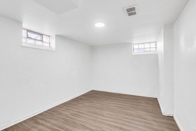 basement featuring visible vents, baseboards, and wood finished floors