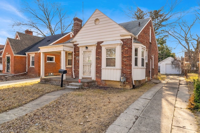 bungalow featuring driveway, a chimney, an outdoor structure, a garage, and brick siding