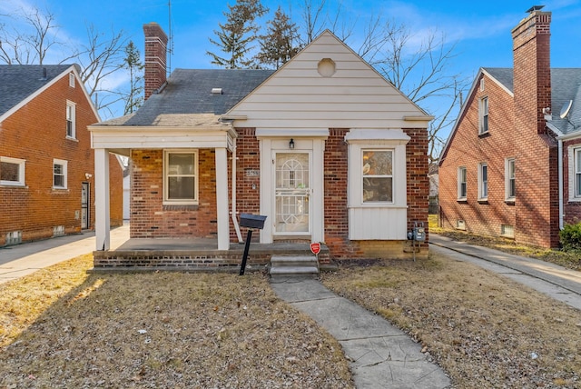 bungalow-style house featuring brick siding, covered porch, and a chimney