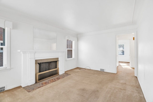 unfurnished living room featuring a fireplace with flush hearth, visible vents, and carpet floors