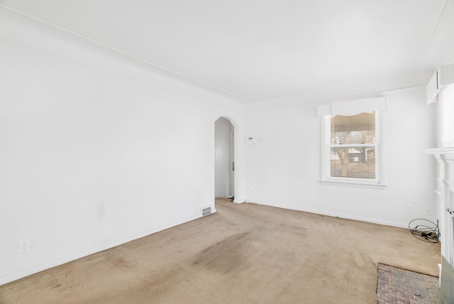 carpeted spare room with arched walkways, visible vents, and baseboards