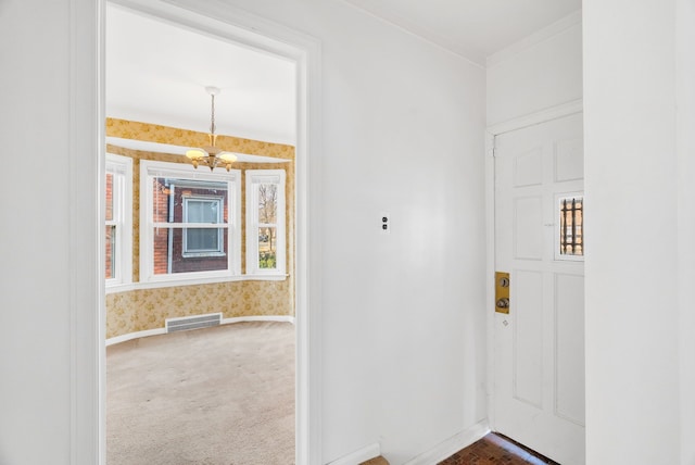 corridor with visible vents, wallpapered walls, baseboards, dark carpet, and an inviting chandelier