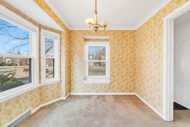 empty room featuring a notable chandelier, wallpapered walls, visible vents, and carpet floors