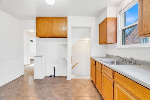 kitchen featuring light countertops, light tile patterned floors, brown cabinets, and a sink